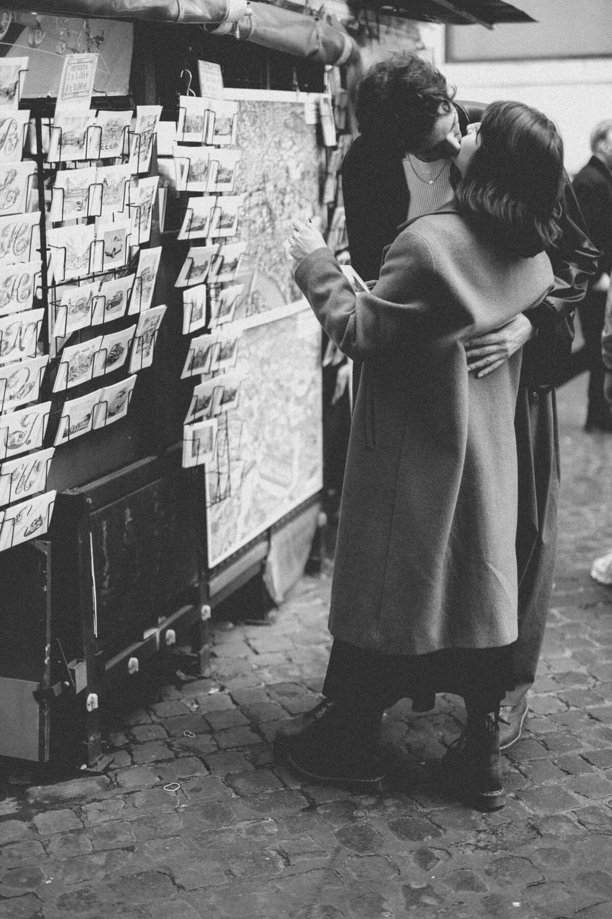 Couple kissing at a postcard kiosk, black and white