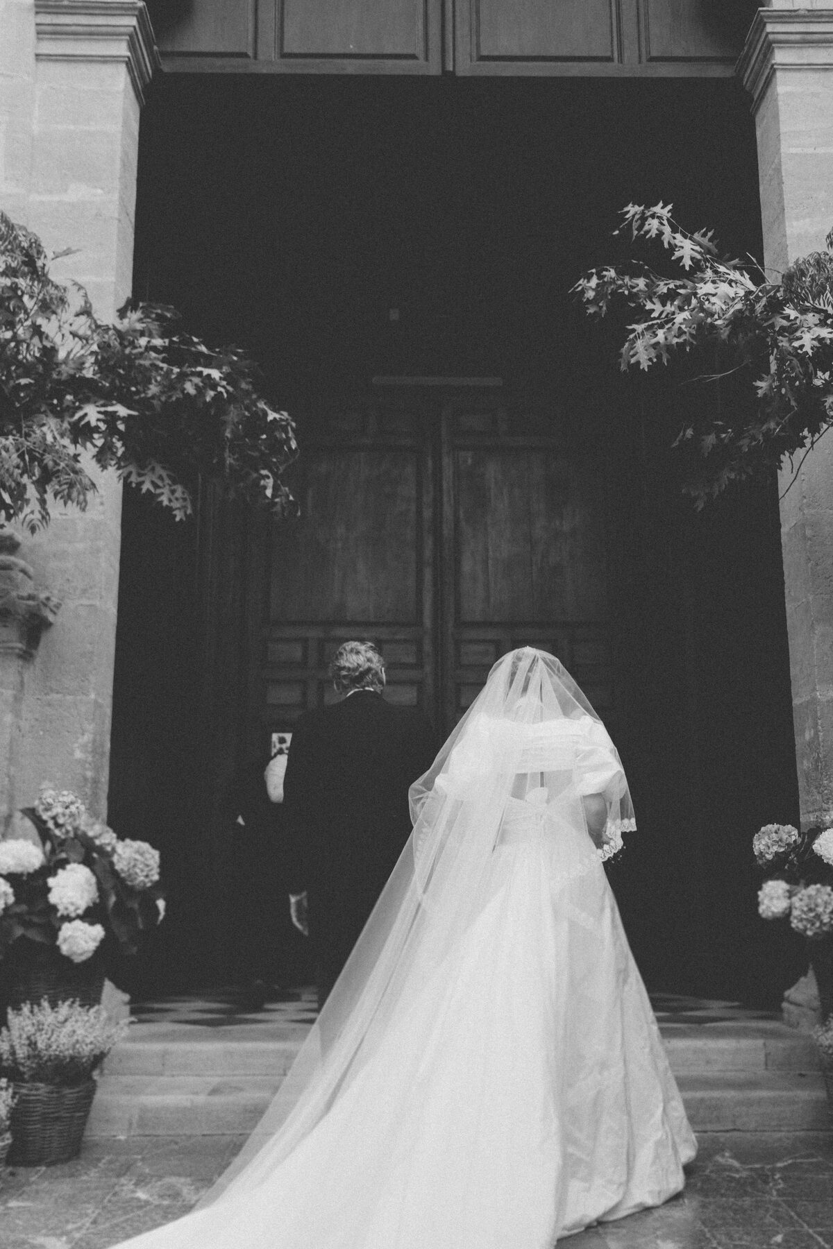 Bride with long veil at an old door, black and white
