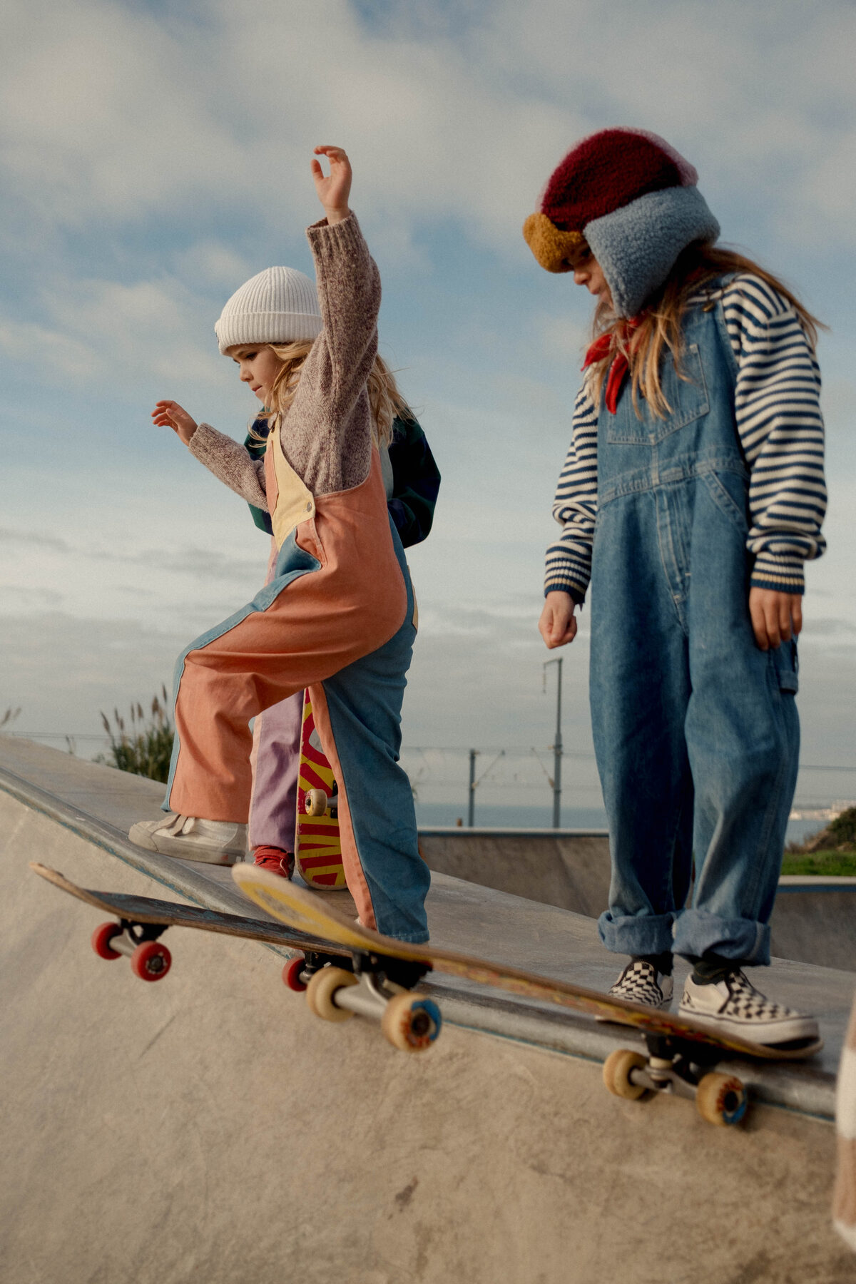Two kids on skateboards against a blue sky